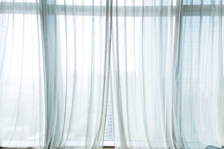 White curtain hanging in the window of a top floor building with city overview