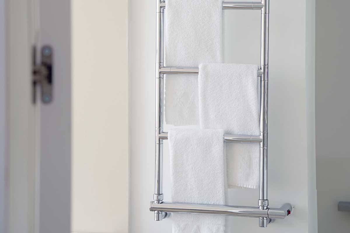 White towels on a chromed heated towel rail in the bathroom