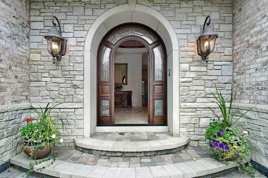 Arched stone entry of luxury suburban home with timber door, Best Front Door Colors For A Gray House