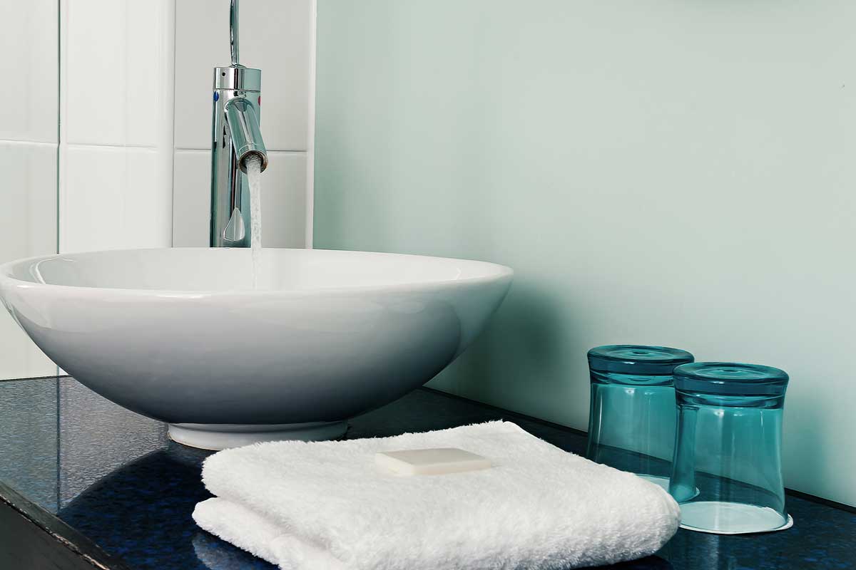 Bathroom sink counter with white towels and blue water glass
