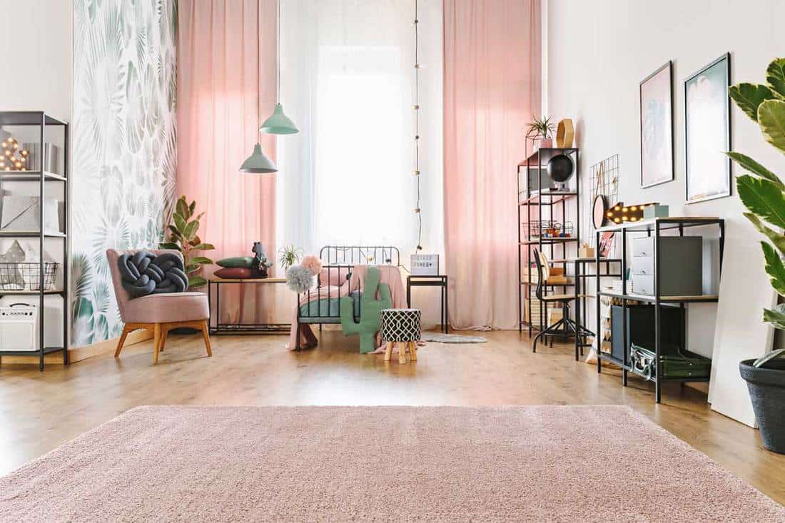 Bright spacious teenage girl room interior with metal bed, pink drapes and soft carpet on the floor, Do Curtains And Rugs Have To Match?