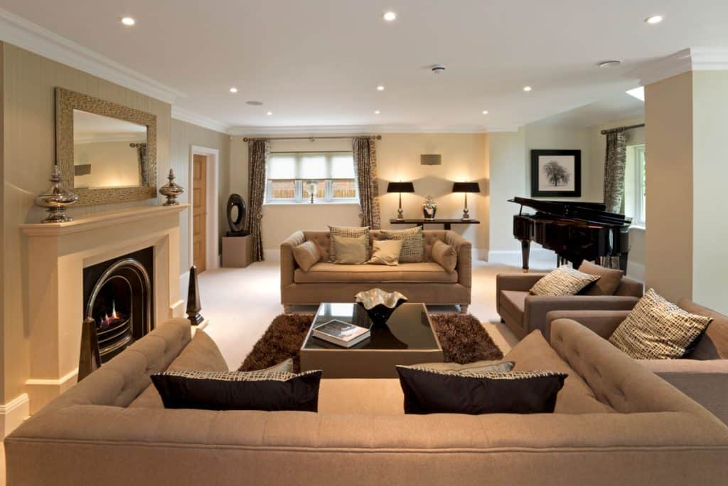 Brown couches with fireplace as centerpiece and white ceiling with ceiling lights
