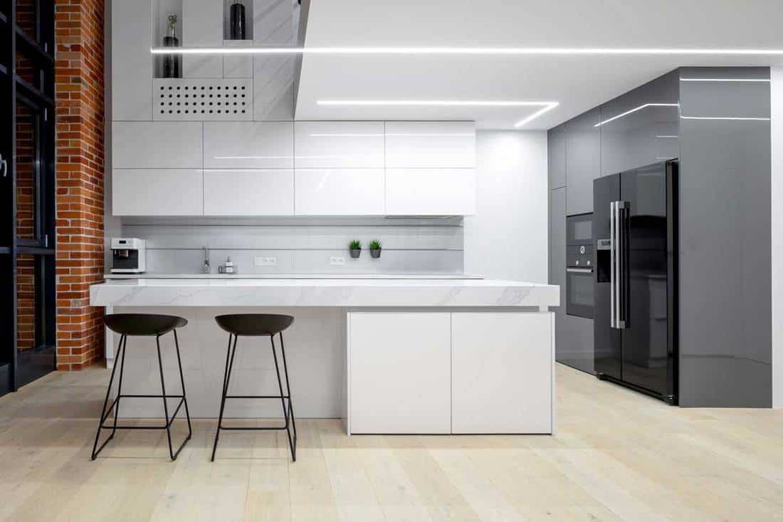 Elegant white and gray kitchen with marble worktop and wooden floor