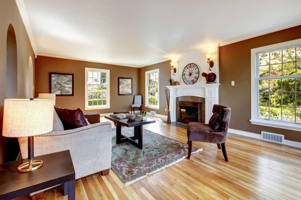 Living room with brown walls wooden flooring and center fireplace