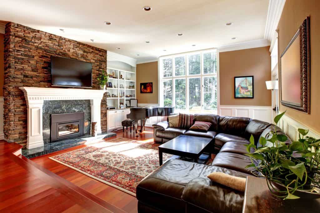 Modern living room with wooden flooring, curved couch, and brown walls with fireplace