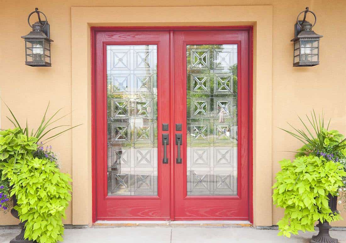 Red glass double doors in an Aztec styled home with peach coloured wall and glass lanterns above the door
