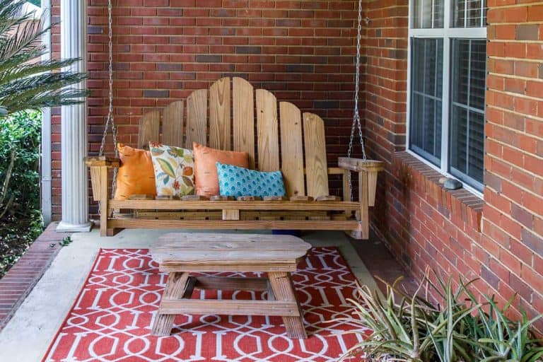 Red brick house outdoor front porch with bohemian decoration, seating and a plant, 27 Red Brick House Front Porch Ideas