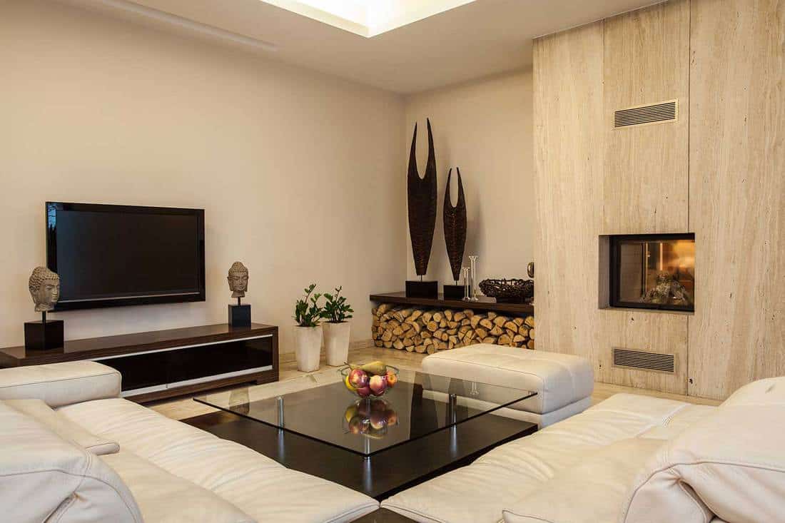 Travertine house interior with cozy white sofa set, TV and fireplace with wooden wall