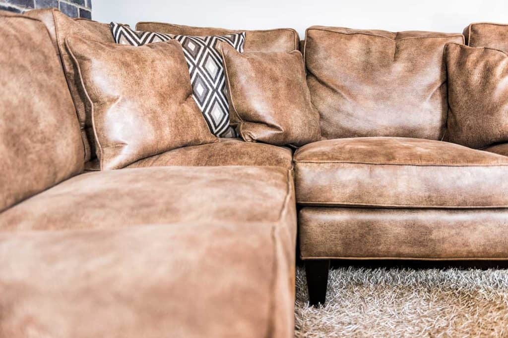 Elegant modern room closeup of a brown leather couch and fluffy rug in staging model house, home or apartment