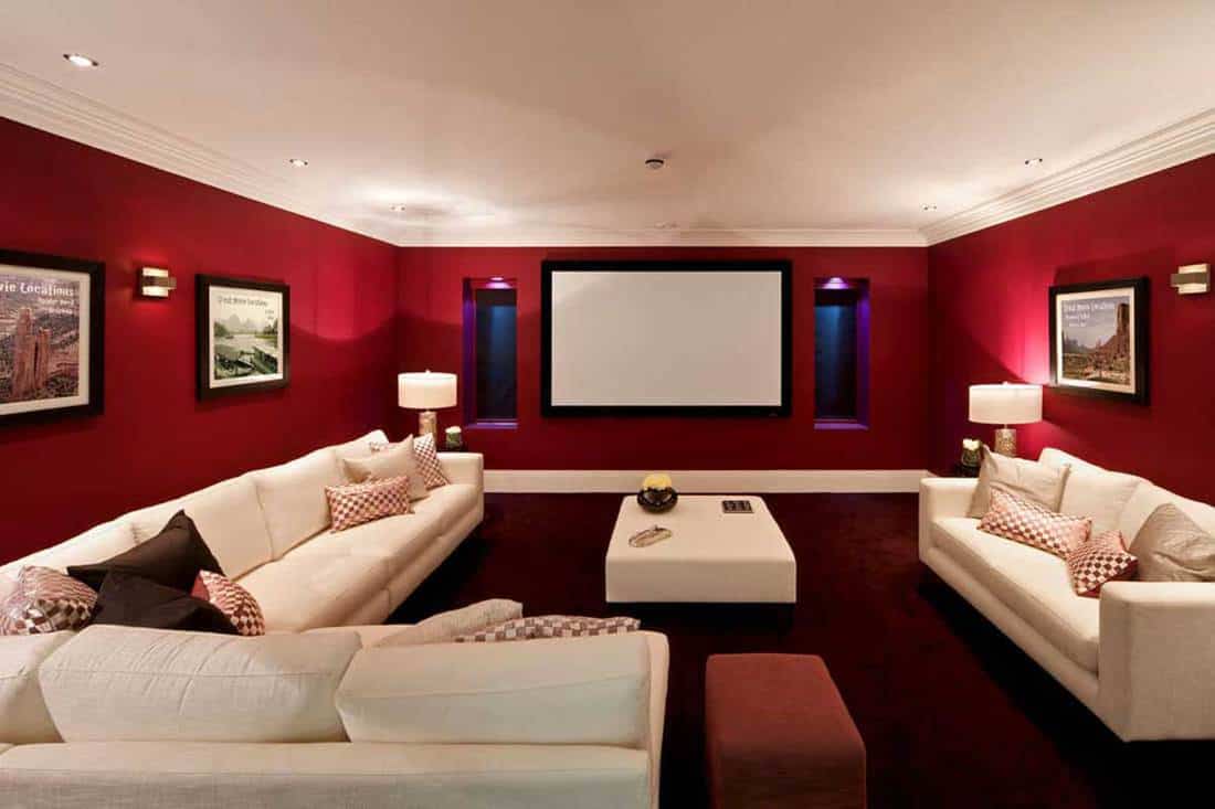 Red Velvet colored wall with pictures hanged and dirty white couch, 21 Wall Decor Ideas For Basement