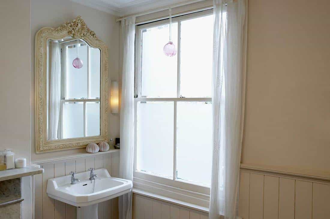 Lavabo et miroir à côté de la fenêtre dans une salle de bains d'un appartement