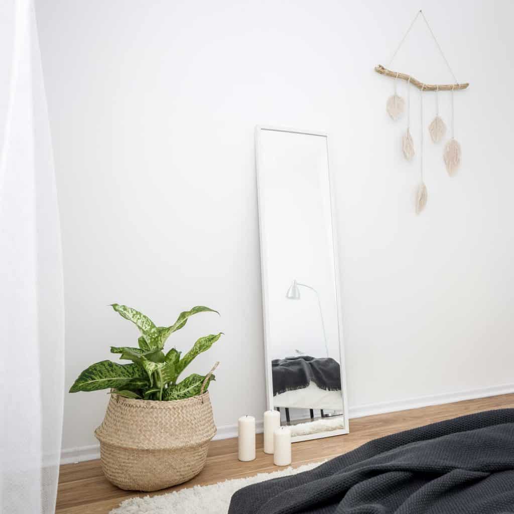 a homey bedroom with medium sized tall floor mirror
