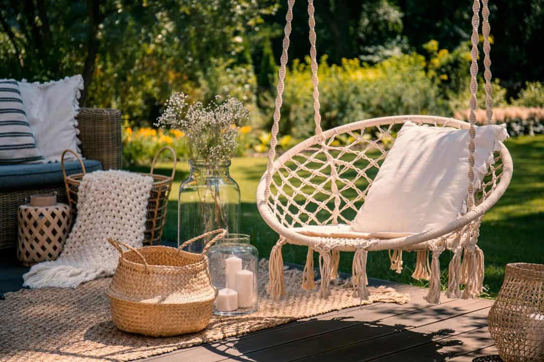 A beige string swing hanging on a relaxing area with a pillow placed on the swing, 18 Front Porch Furniture Ideas