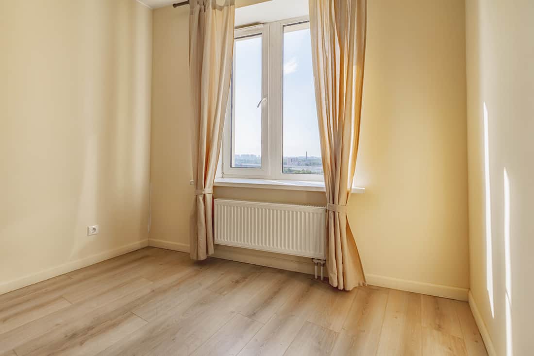 A beige wall with long tied-back beige curtains