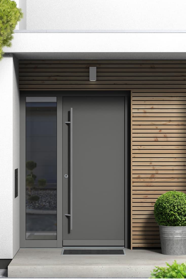 A porch of a contemporary house with gray aluminum door and a trellis like cladding