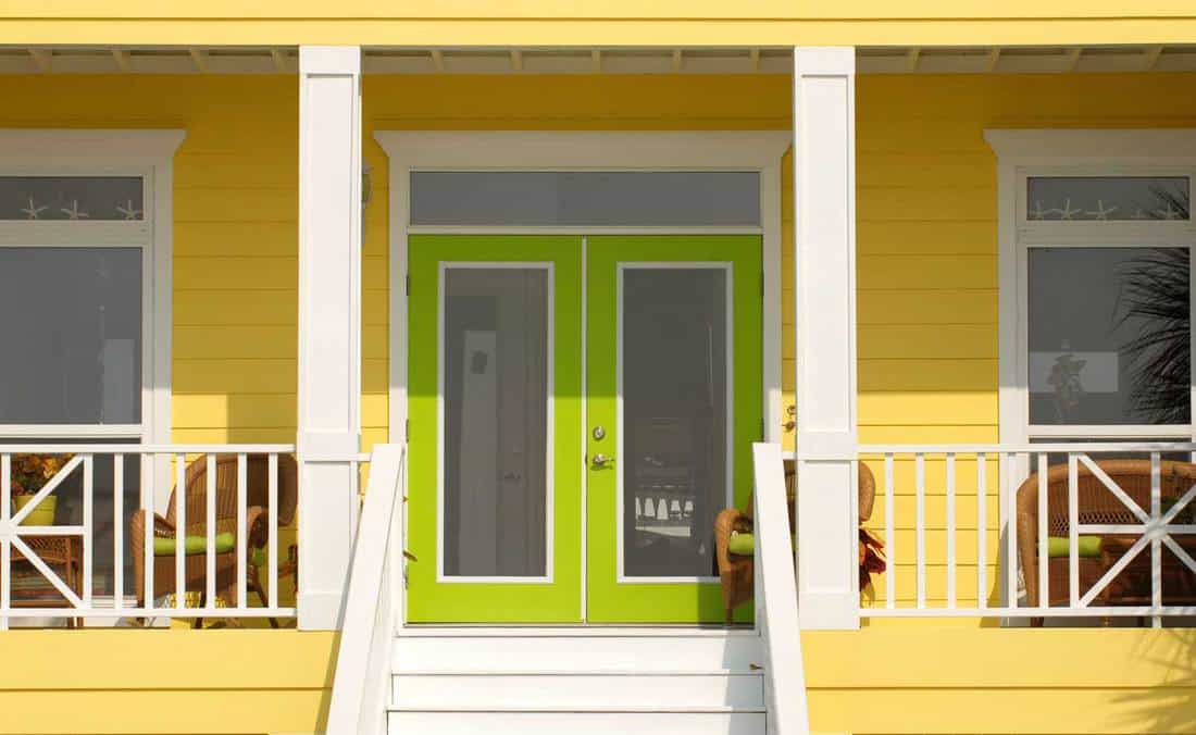 A very colorful entrance way to a yellow home with green doors in Pensacola Florida