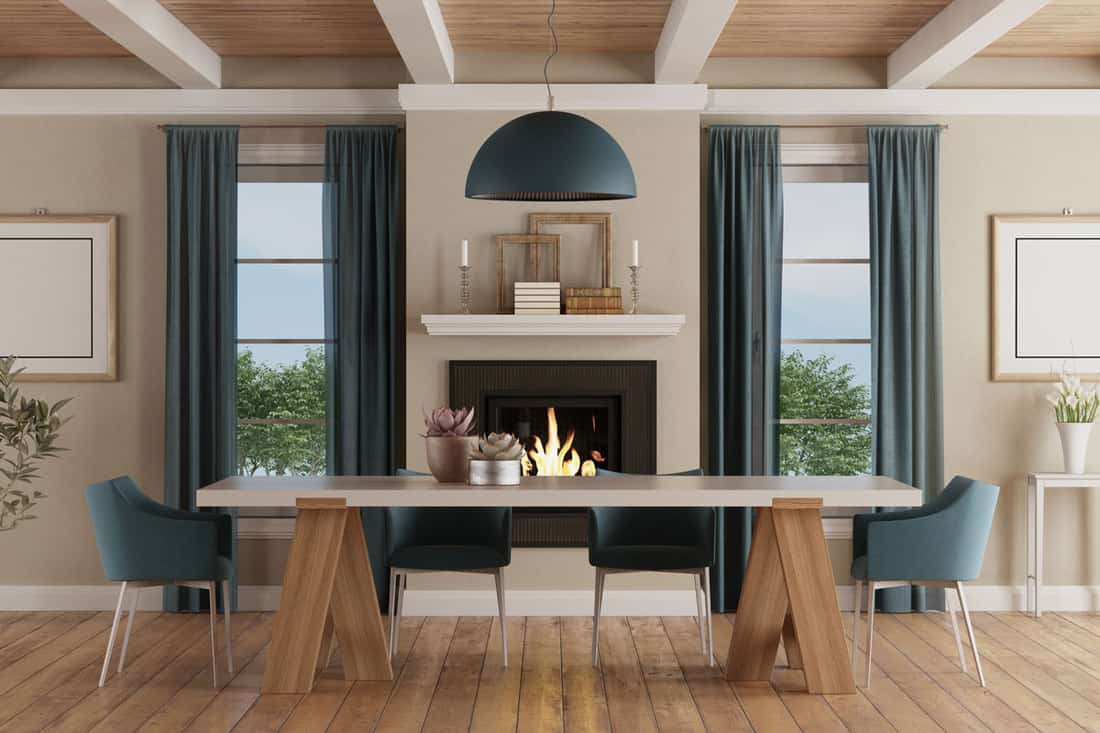 Dark blue colored curtains on beige colored walls with a fireplace and long rectangular table at the middle