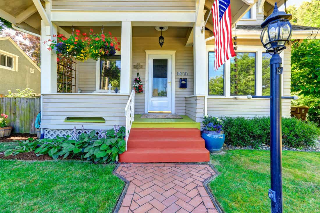 Front porch of a rustic type house with the american flag hanged in front