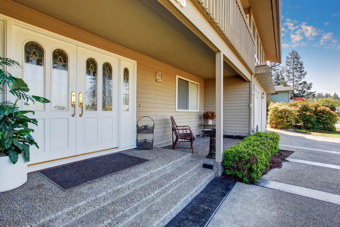 Front porch with white double door and pebble patterned flooring
