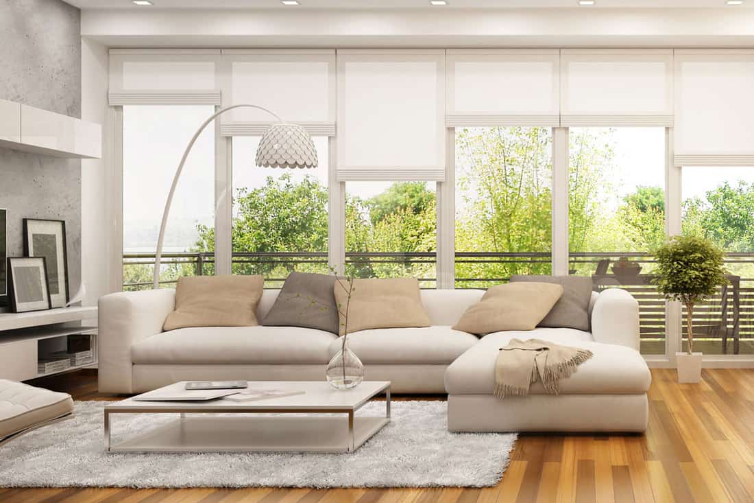 Spacious living room with beige colored sofa placed near huge window