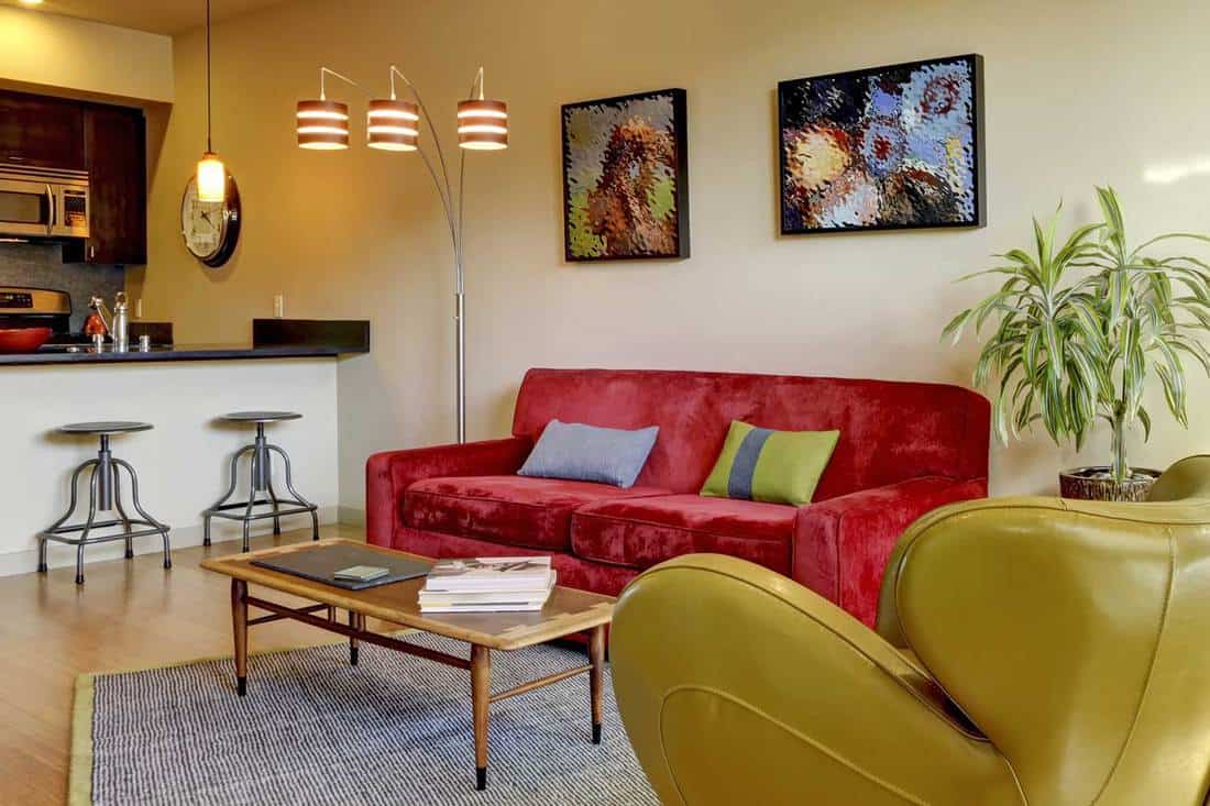 Yellow large modern living room with red couch and paintings on the wall