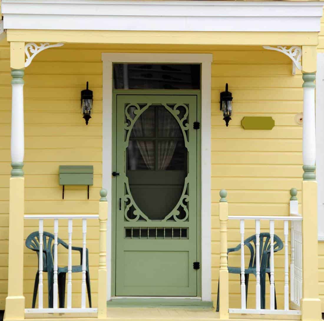 a meticulously painted yellow victorian home with an ornate spring green door