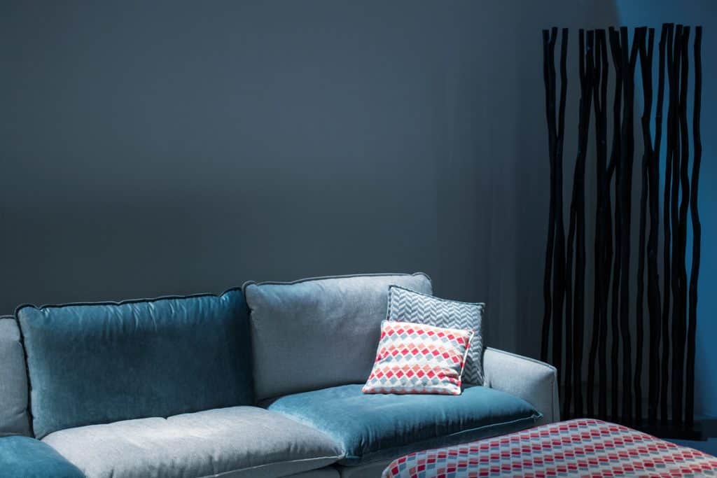 A blue colored couch with matching blue walls