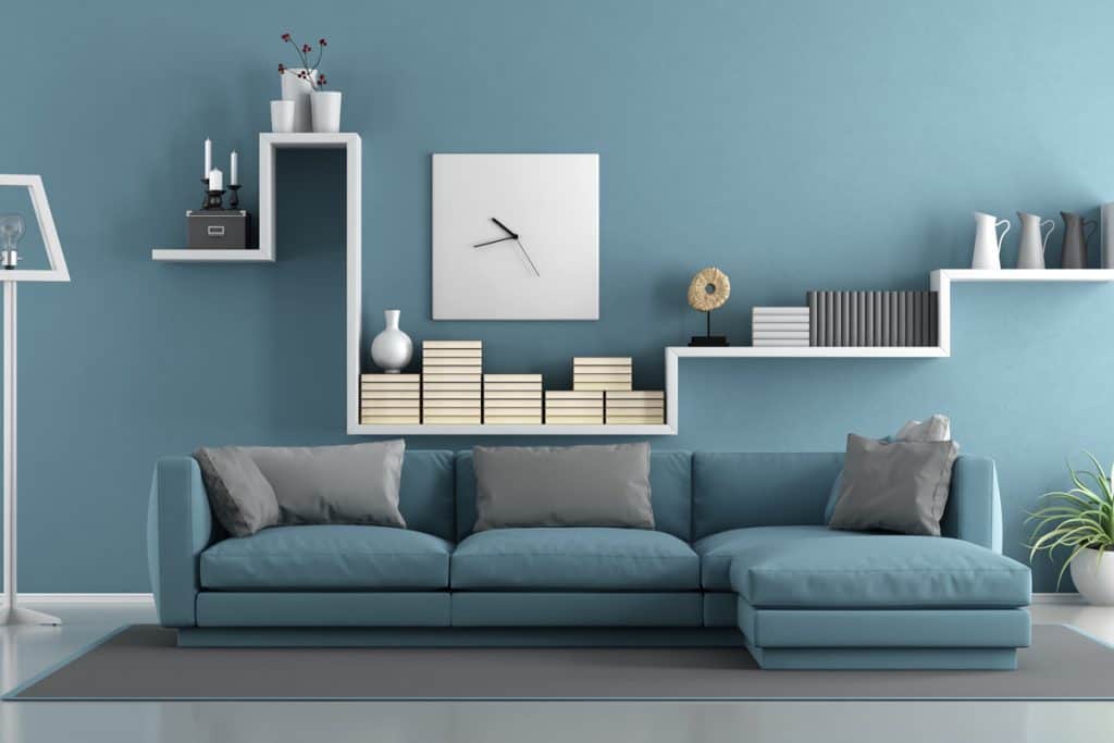 A blue colored wall with an abstract designed cabinet and blue couch