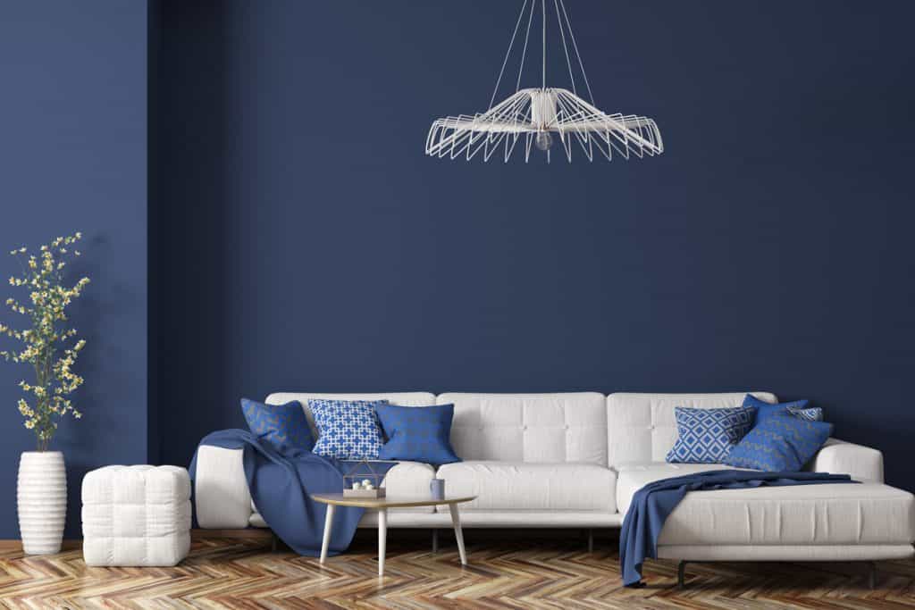 Un salon bleu avec un canapé blanc et un sol marron