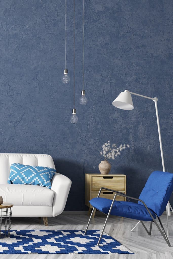 Un salon à thème bleu avec un canapé blanc et un meuble marron près du mur