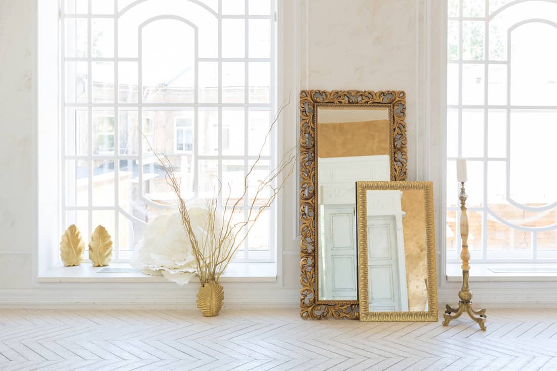 A white empty room with a classy mirror placed next to a wall