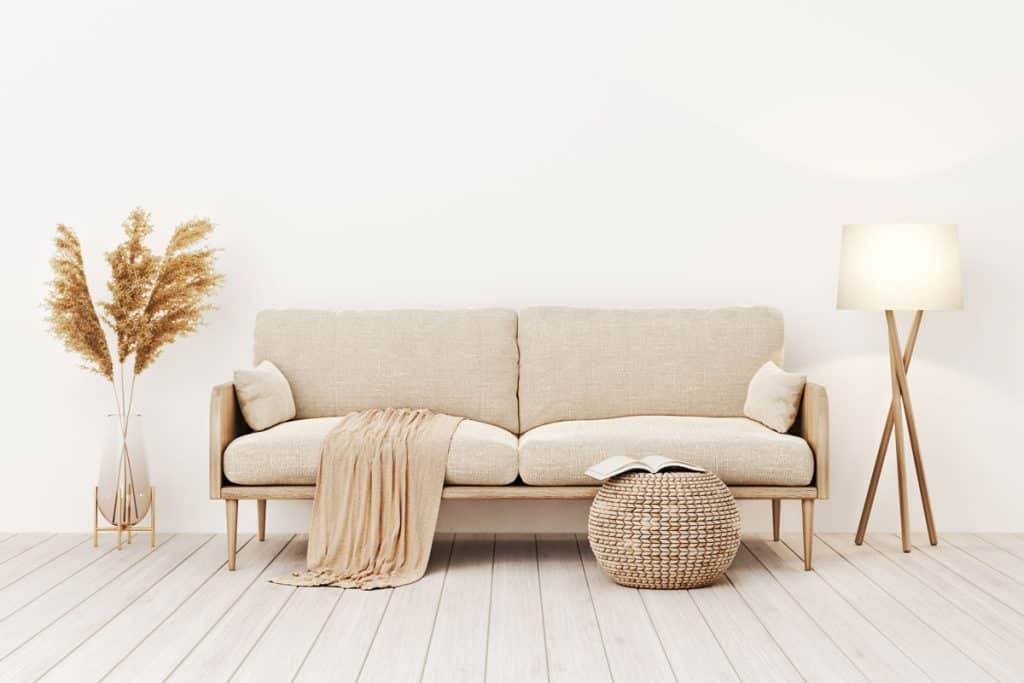 Beige sofa matching the throw and a small pouf upfront