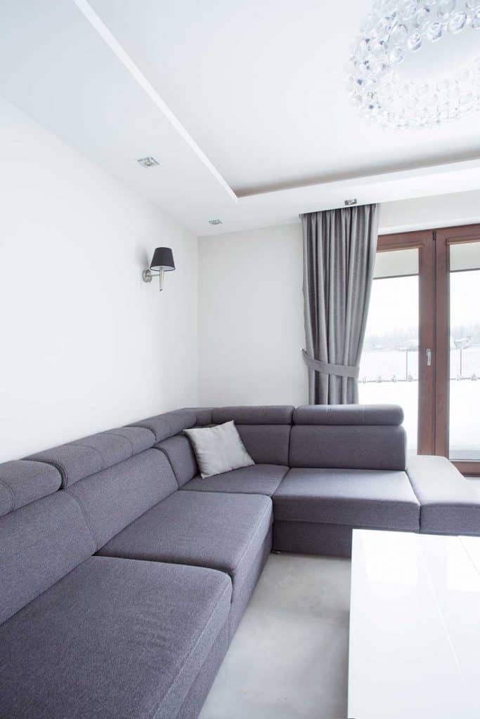 Grey corner sofa in modern living room with chandelier