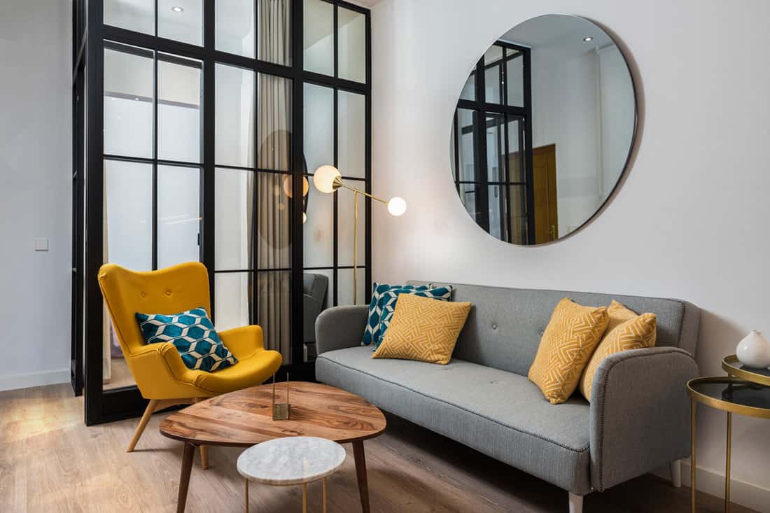Interior of a modern living room with a gray contemporary sofa with yellow and blue throw pillows