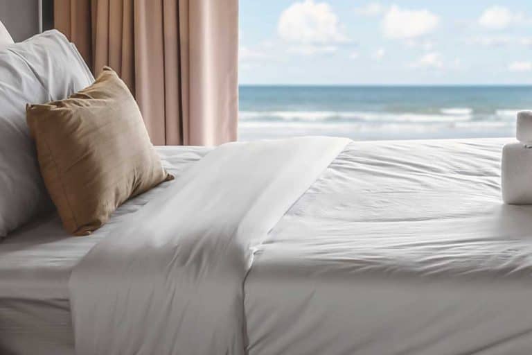 Luxury hotel bedroom with seaview on large glass sliding door, How to Wash White Sheets [Inc. How Hotels Keep Sheets White!]