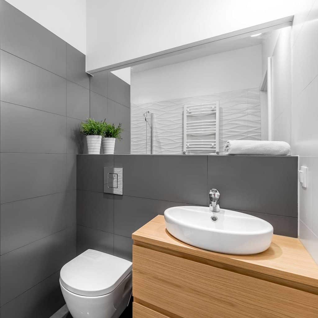 Modern grey bathroom with shower, wooden cabinet, round, white basin and toilet
