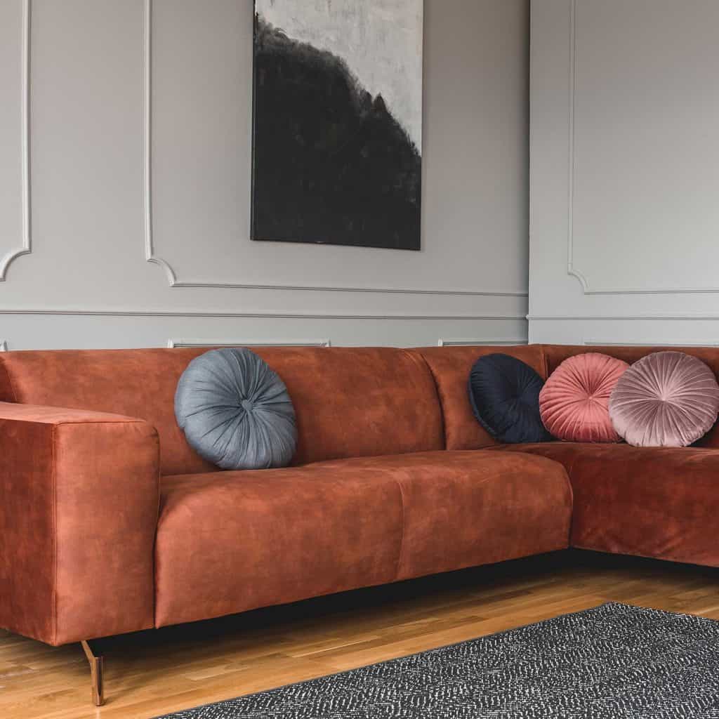 Round velvet pillows on brown living room sofa