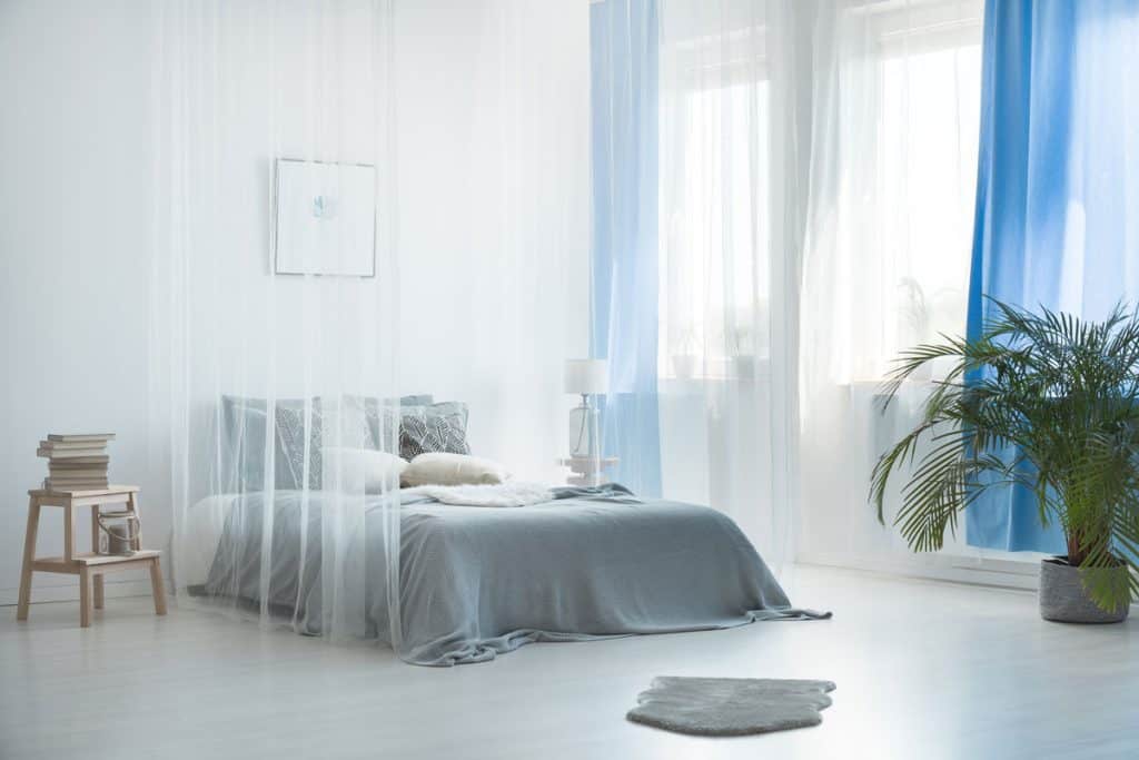 White drapes and blue curtains inside nautical themed bedroom