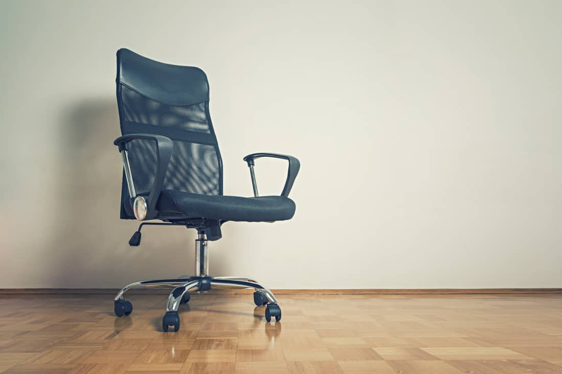 A blue office chair placed at the corner of a room , Should You Get A Cushion For Your Office Chair?