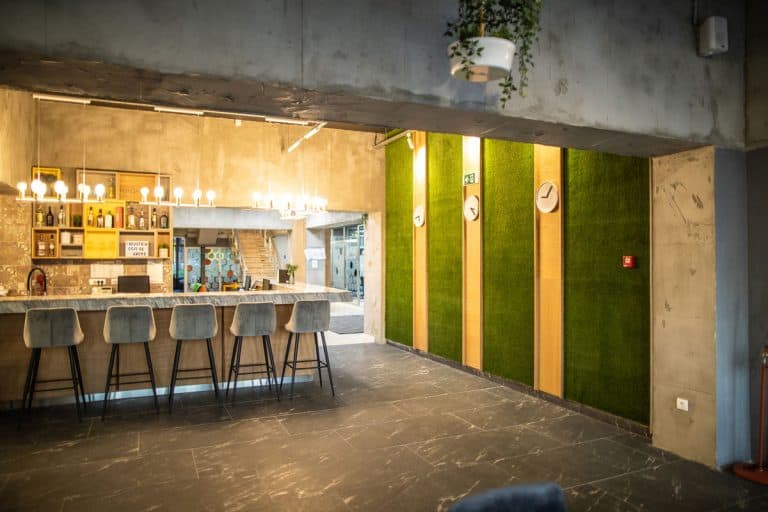 A modern bar with five bar stools and a grass textured decorative wall, How Tall Should Bar Stools Be? [Results by bar height]
