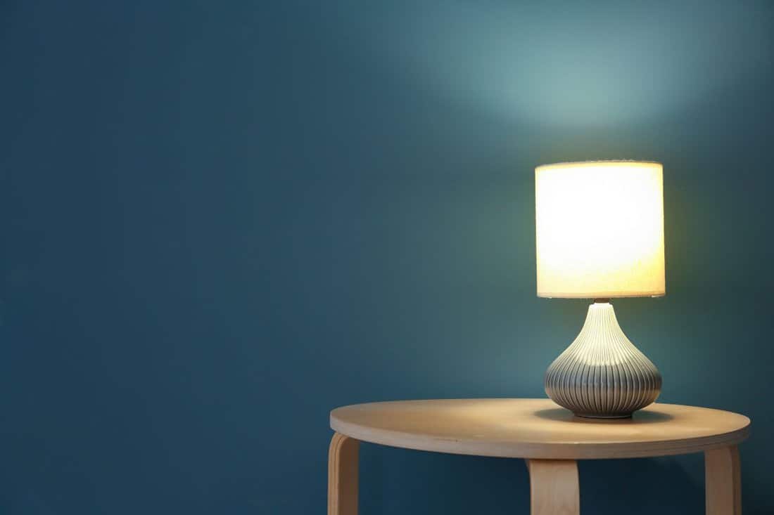 Elegant lamp on table near color wall.