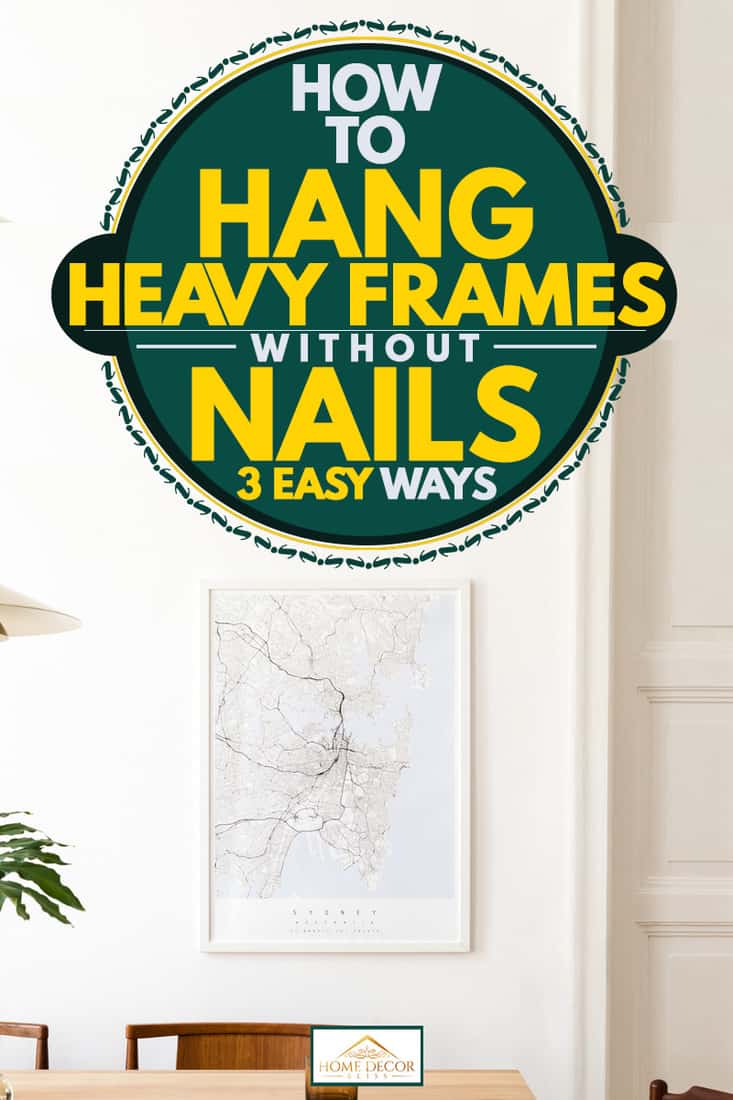 A modern dining room with a framed map hanging on a white wall, How To Hang Heavy Frames Without Nails [3 Easy Ways]