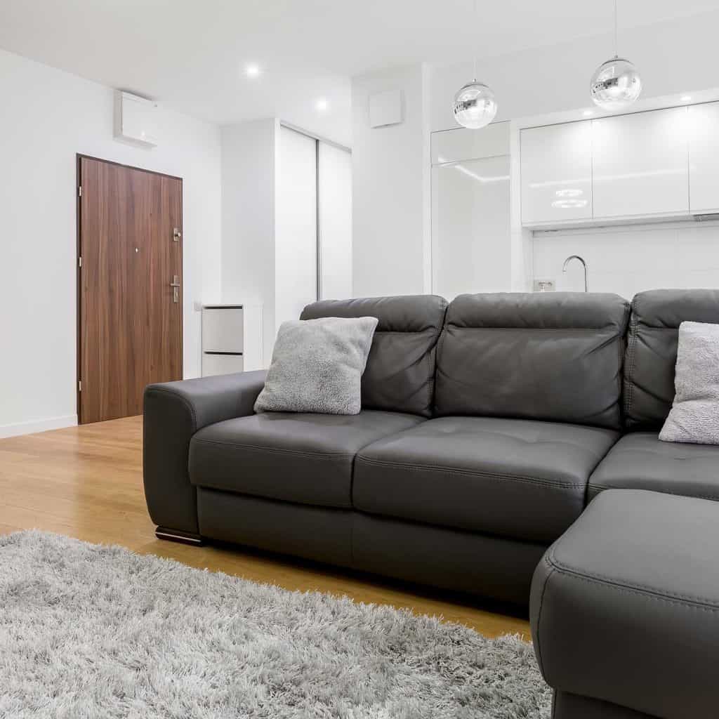 Living room with big black leather sofa in modern flat