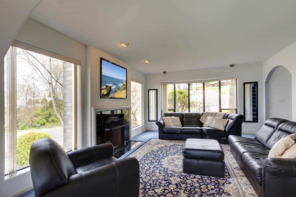 Modern living room interior with black leather sofa set, tv, carpet and glass windows