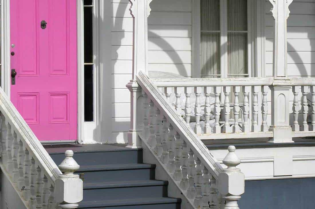 Pink exterior door on white Victorian house, 15 Types of Porches Every Homeowner Should Know