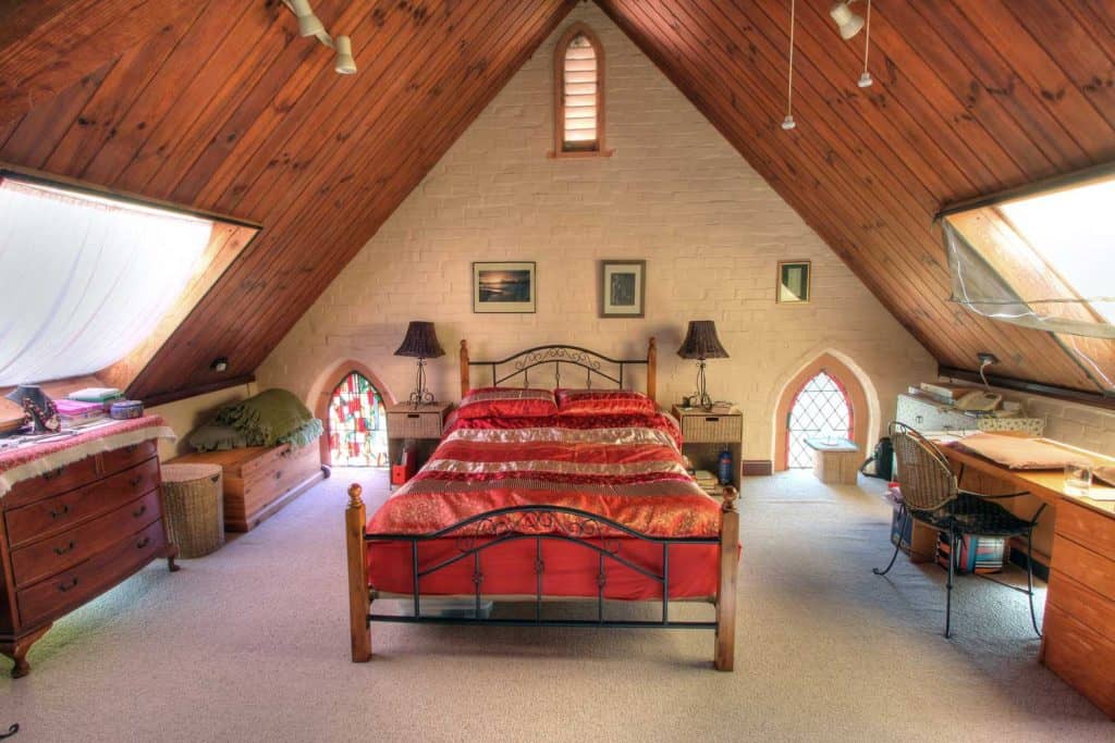 Stylish king size bedroom in the attic with windows on both sides