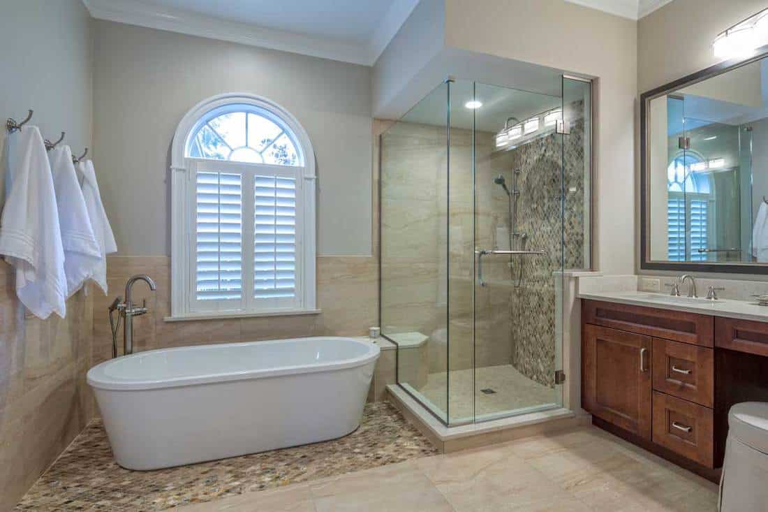 A complete remodeled master bathroom interior with hinged shower door