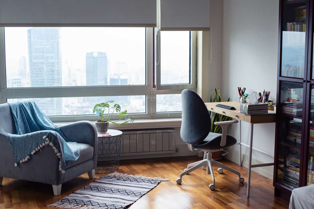 A modern apartment with a computer desk on the side and a small accent chair on the left, What is The Standard Height of a Desk? [And how to find the ideal desk height for you]