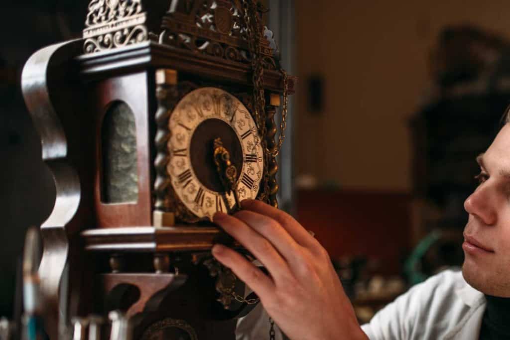 Een horlogemaker repareert de oude staande klok, hoeveel kost het om een ​​grootvaderklok te onderhouden?