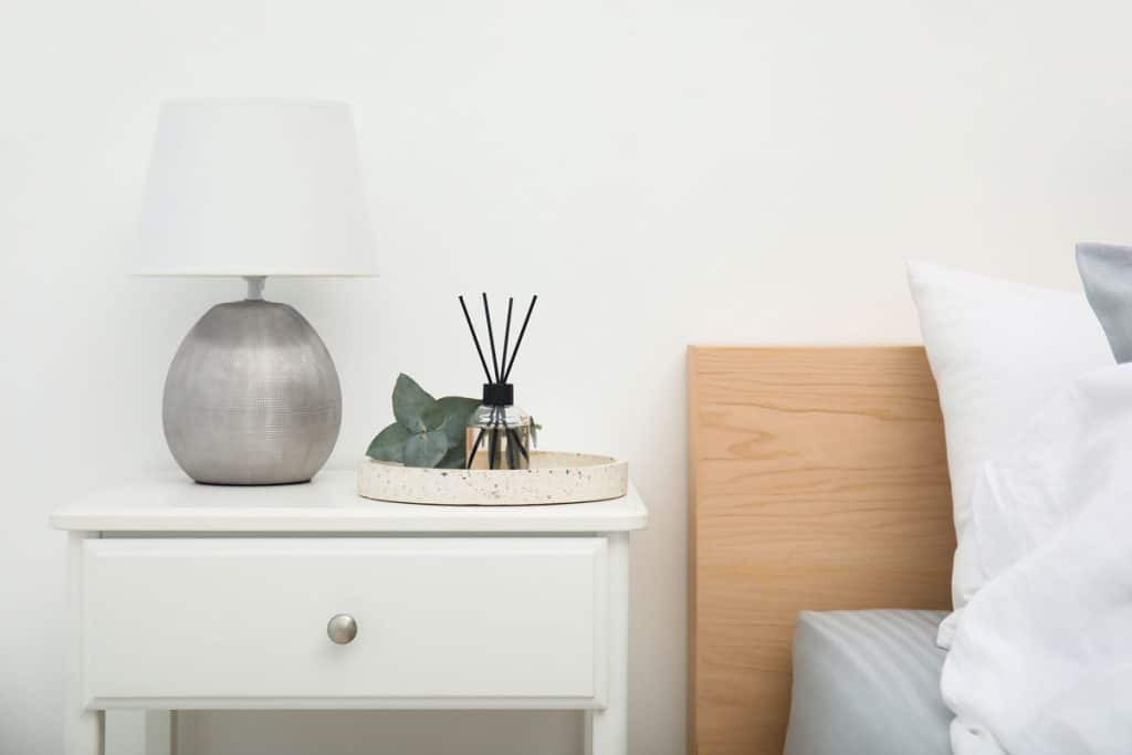 A white nightstand with a gray lamp on top